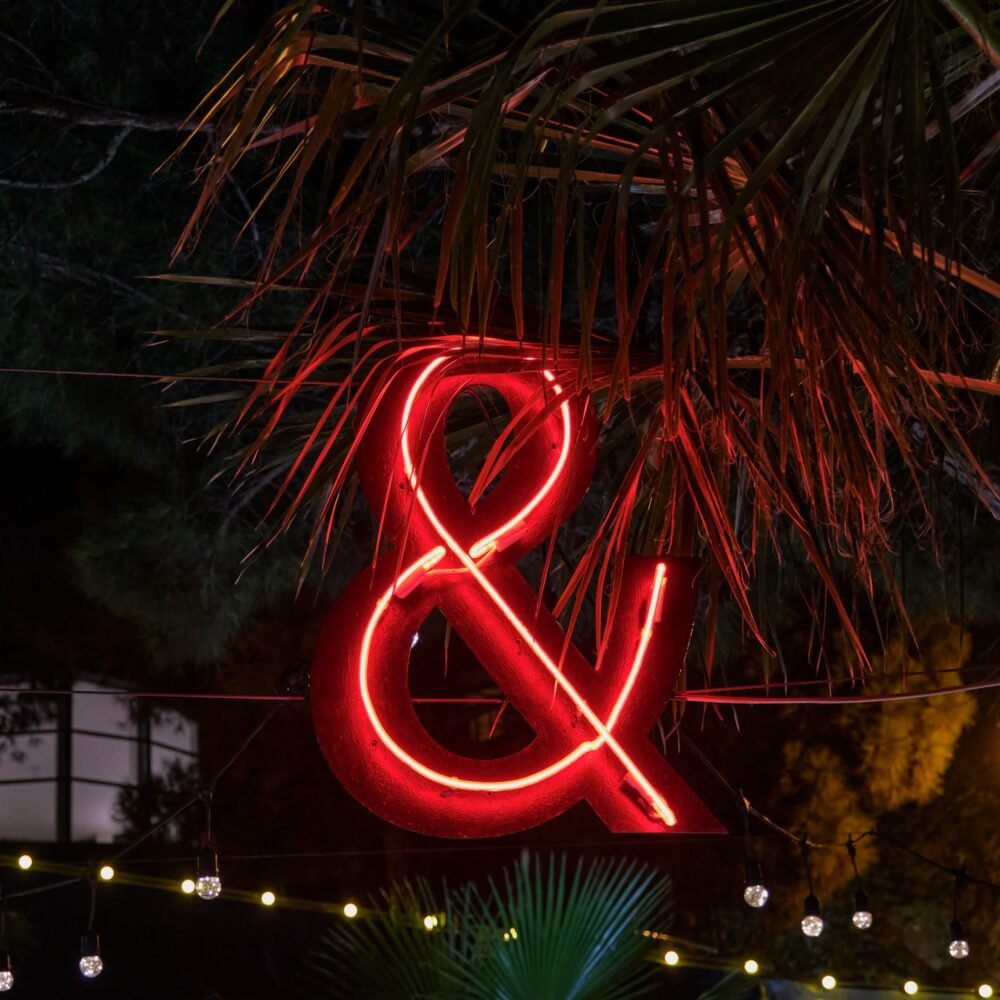 Evening lighting in the form of a luminous neon red ampersand sign.